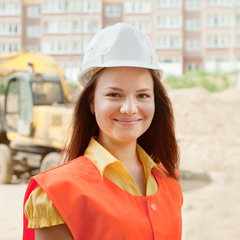 Une femme souriante avec un casque sur un chantier de construction