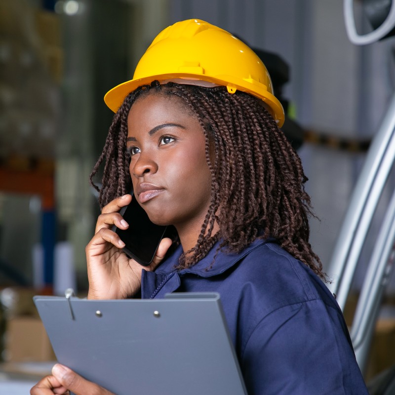 Une femme avec un casque jaune dans un entrepôt logistique