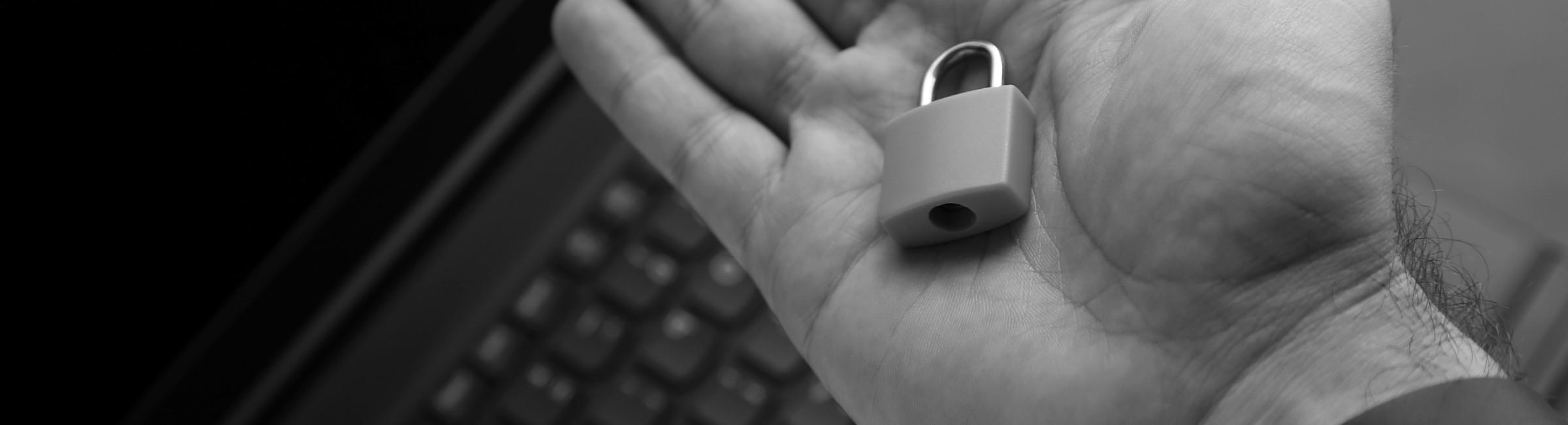 Un homme tient un cadenas dans sa main devant son ordinateur